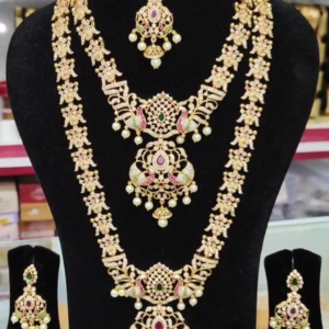 22K gold-plated royal bridal temple necklace set with ruby, emerald, zirconia accents, pearls, and two necklaces (short and long), featuring intricate designs and matching earrings.