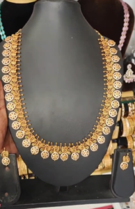 22K gold-plated traditional temple necklace set with ruby, emerald, and zirconia accents, featuring intricate designs and matching earrings