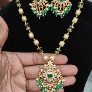 A 20-inch gold-toned necklace with a central emerald-cut green stone, surrounded by smaller clear stones and delicate green pearl drops, Matching earrings with similar design and dangling pearls are also shown.